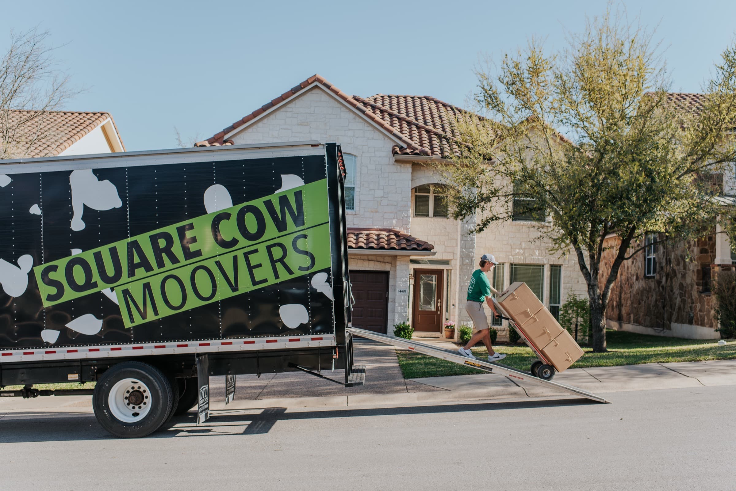 A Square Cow Moovers truck unloading boxes at a home